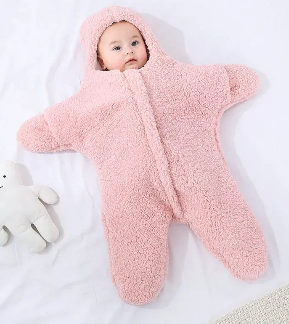 Baby in a pink fluffy snowsuit lying on a white surface